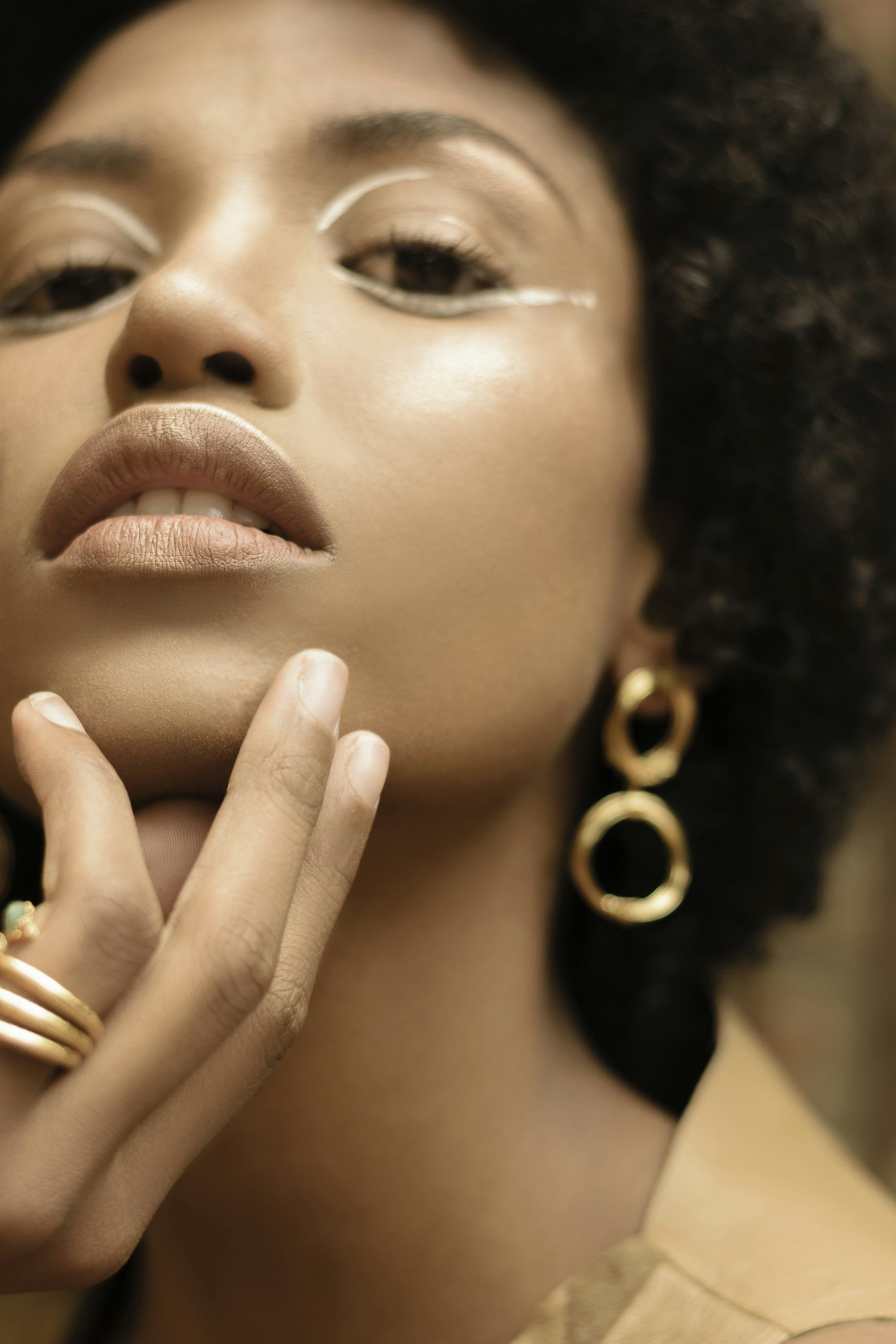Primer plano de una modelo con pendientes de aros dorados y anillos de oro